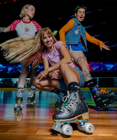 Three people roller skating on a wooden floor with a colorful background